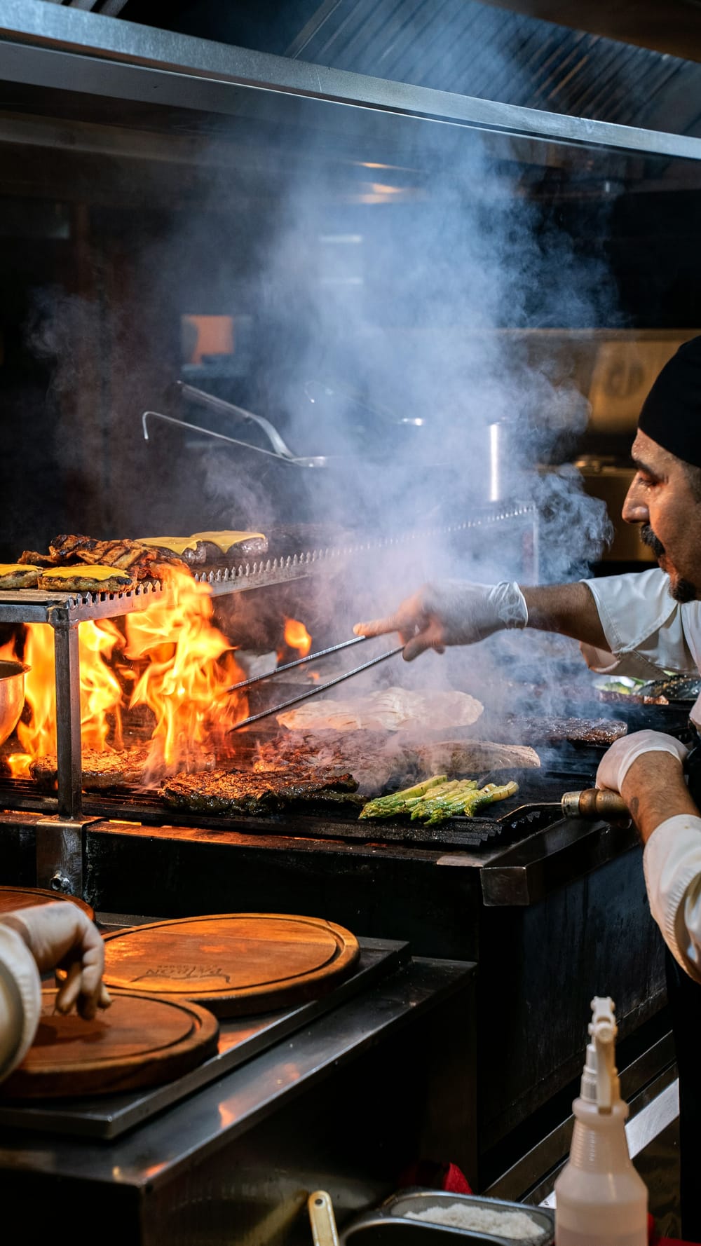 Chef cooking over open flame in a restaurant kitchen